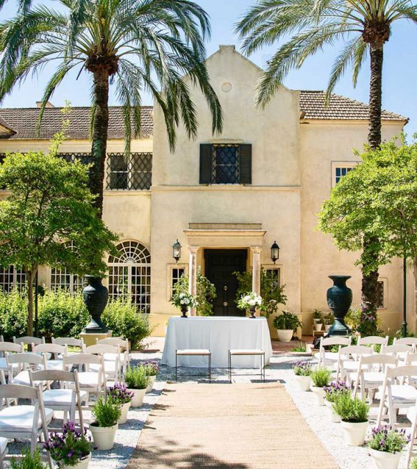 Decoración para boda civil con sillas blancas y flores en la entrada principal de una finca, organizada por Antonio Bort en Espartinas, Sevilla.