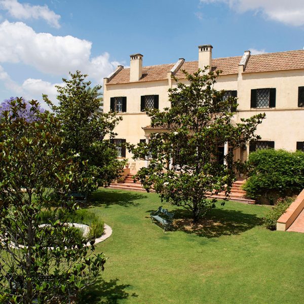 Fachada de finca rodeada de zonas verdes y árboles, ideal para celebraciones organizadas por Antonio Bort en Espartinas, Sevilla.